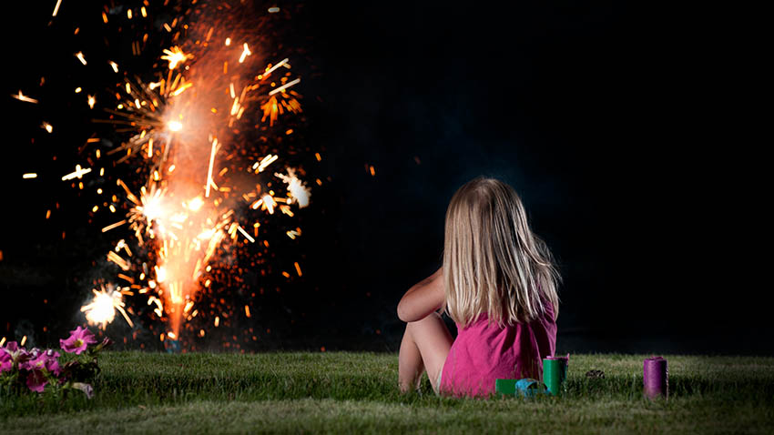 小女孩坐在草地上看烟花