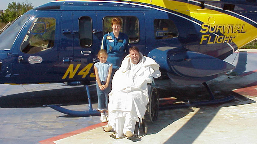 幸存的飞行病人和女儿与工作人员在黄色和蓝色密歇根直升机前
