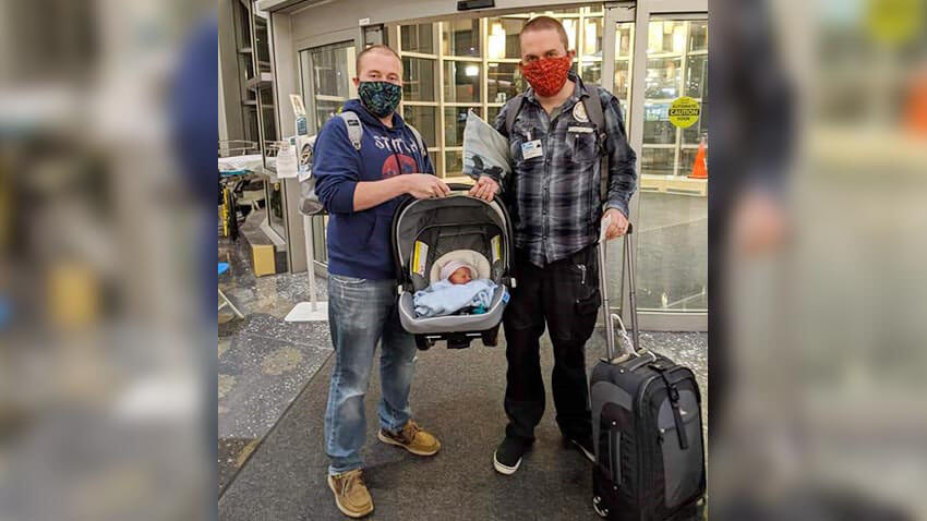拿着新的婴孩的两个父母在机场