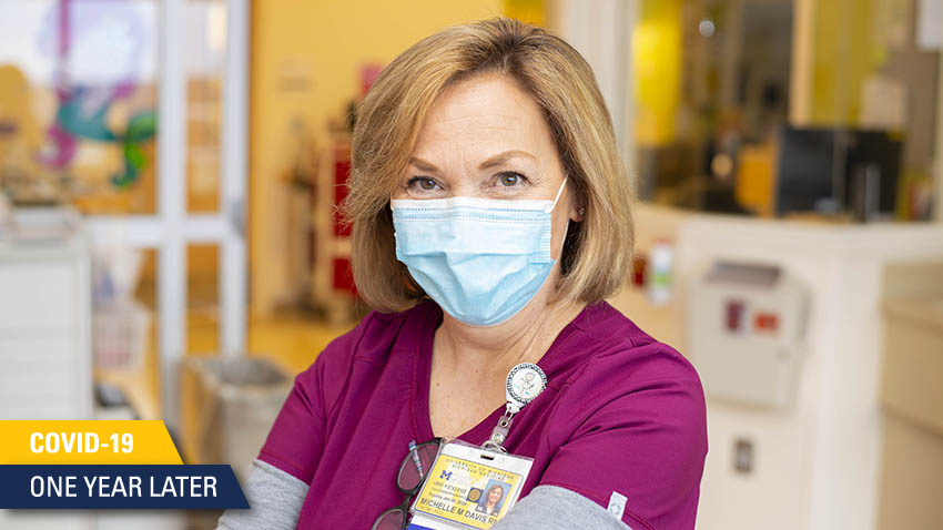护士穿着栗色的手术服戴着浅蓝色的面具对着镜头微笑