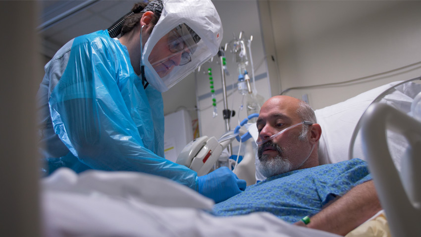 医护人员与正在服用新冠病毒的患者在床上