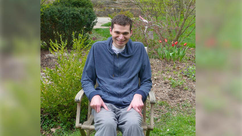 坐在轮椅上的男人在花圃边微笑
