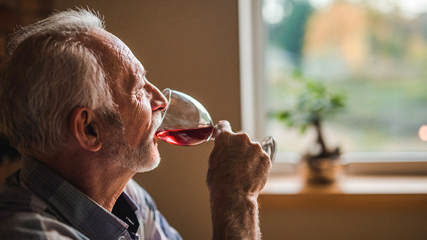 老人用玻璃杯喝红酒