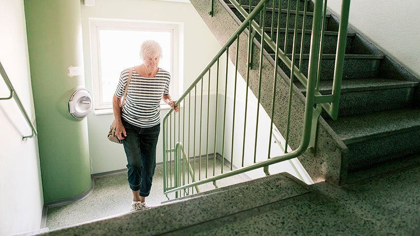 老年妇女爬楼梯，扶栏杆