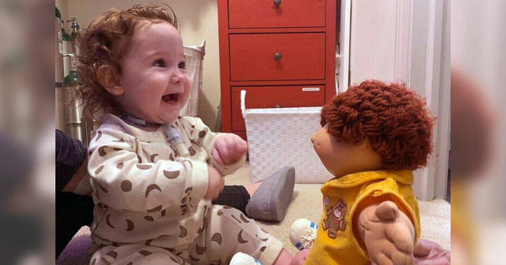 带着管子的婴儿在房间里和娃娃一起玩