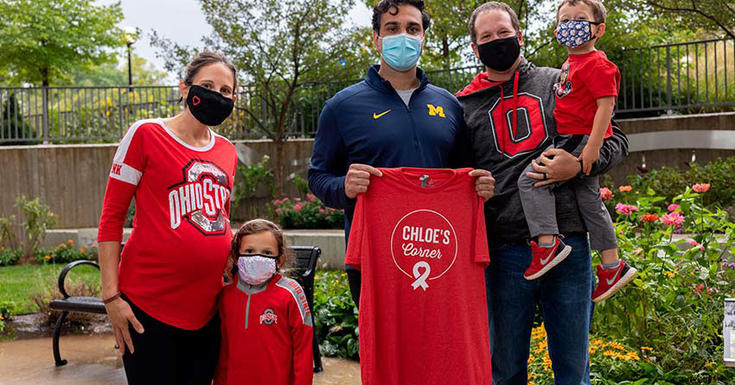 戴着面具的家人穿着俄亥俄州密歇根的红衫站在院子里。